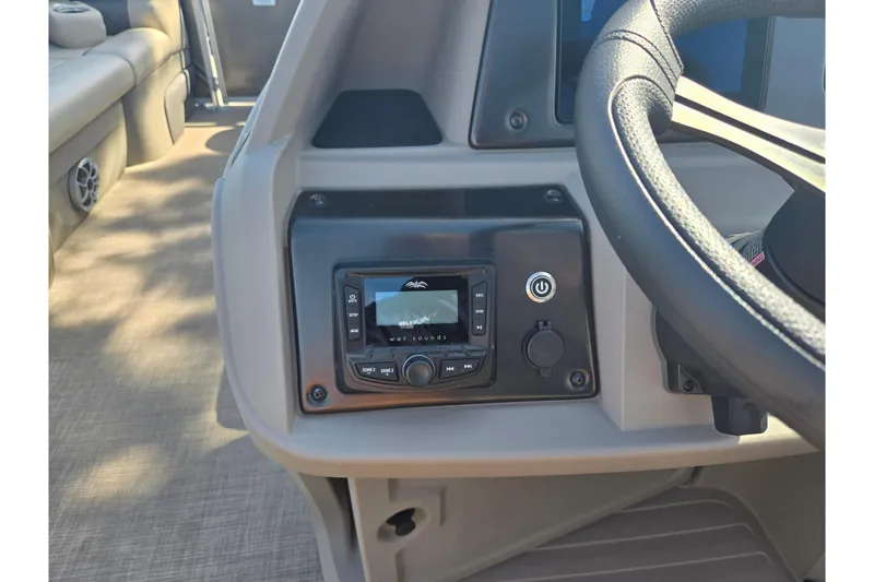 Slide: The Image of 2024 Sun Tracker Party Barge 20 DLX dashboard with audio controls and steering wheel. - 22
