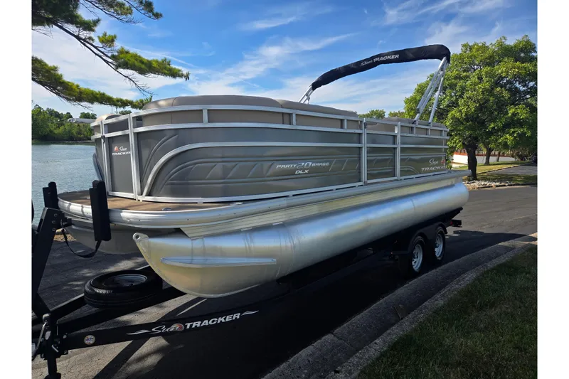 Slide: The Image of 2024 Sun Tracker Party Barge 20 DLX pontoon boat on trailer by a lake. - 8