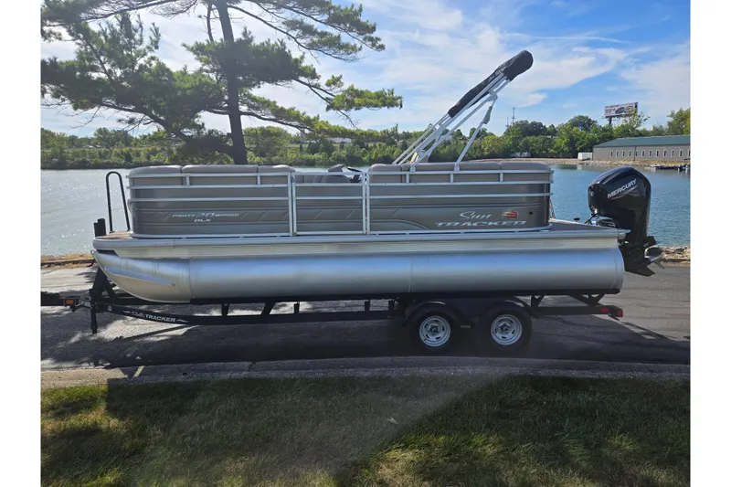 Slide: The Image of 2024 Sun Tracker Party Barge 20 DLX pontoon boat on trailer by a lake. - 9