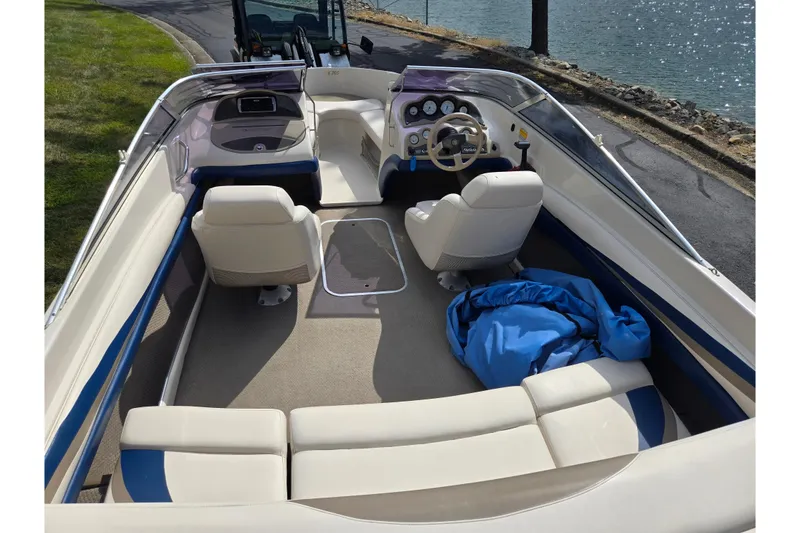 Slide: The Image of 2001 Glastron GX 205 boat interior with white seating and blue accents by the water. - 10