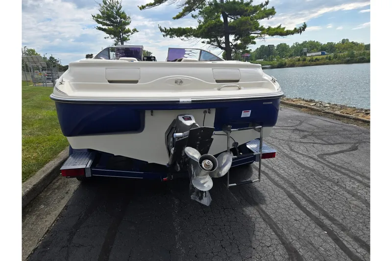 Slide: The Image of 2001 Glastron GX 205 boat on trailer by a lakeside road. - 2