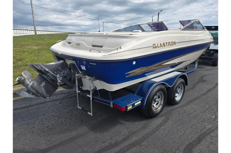 Slide: The Image of 2001 Glastron GX 205 boat on trailer, blue and white design, parked on asphalt. - 3