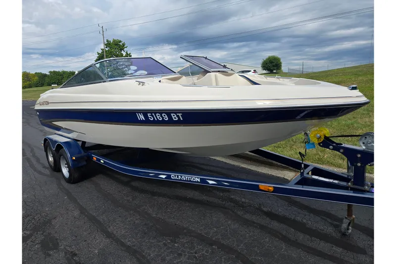 Slide: The Image of 2001 Glastron GX 205 boat on trailer, parked on asphalt, under cloudy sky. - 5