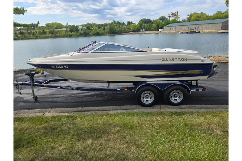 Slide: The Image of 2001 Glastron GX 205 boat on trailer by a lakeside road. - 9
