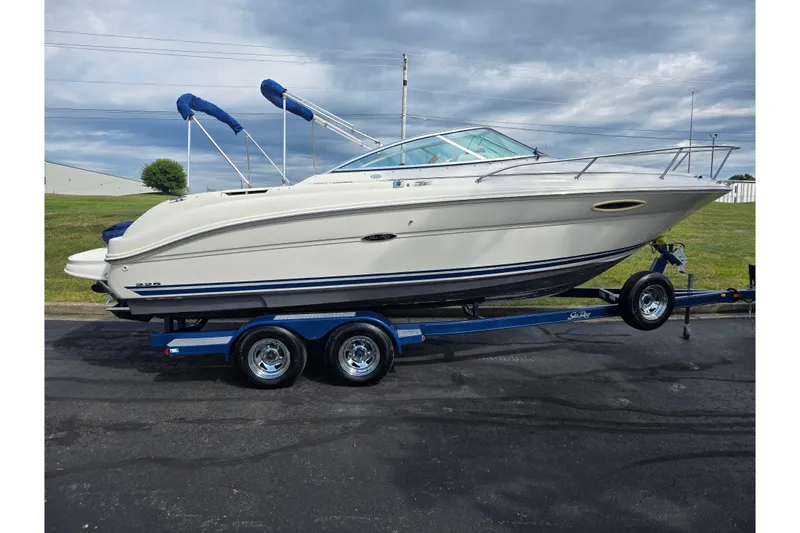 Slide: The Image of 2002 Sea Ray 225 Weekender boat on trailer, parked outdoors under cloudy sky. - 4