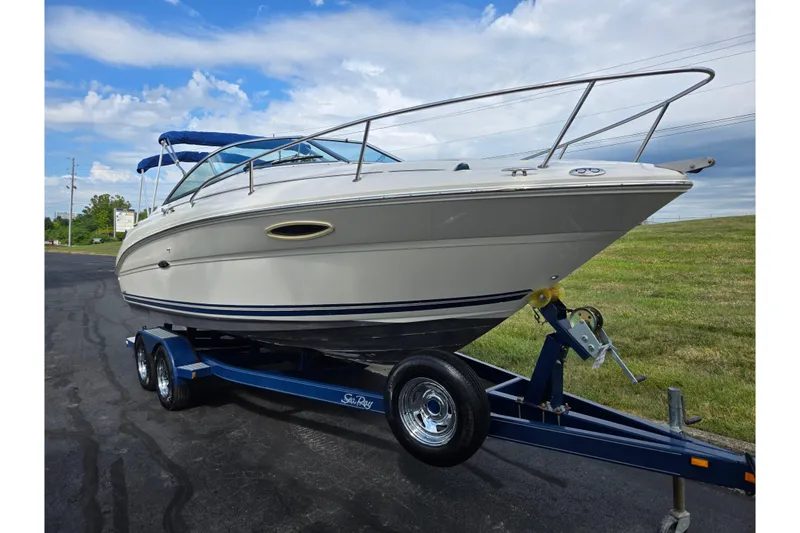 Slide: The Image of 2002 Sea Ray 225 Weekender boat on trailer, parked on asphalt, under blue sky. - 5