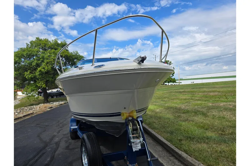 Slide: The Image of 2002 Sea Ray 225 Weekender boat on trailer, parked on a paved road, under a blue sky. - 6