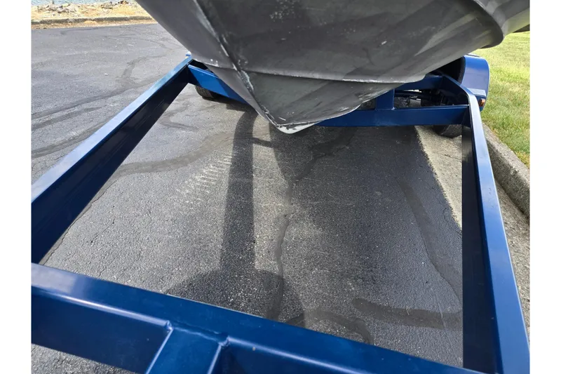 Slide: The Image of 2002 Sea Ray 225 Weekender boat on a blue trailer, parked on asphalt. - 7