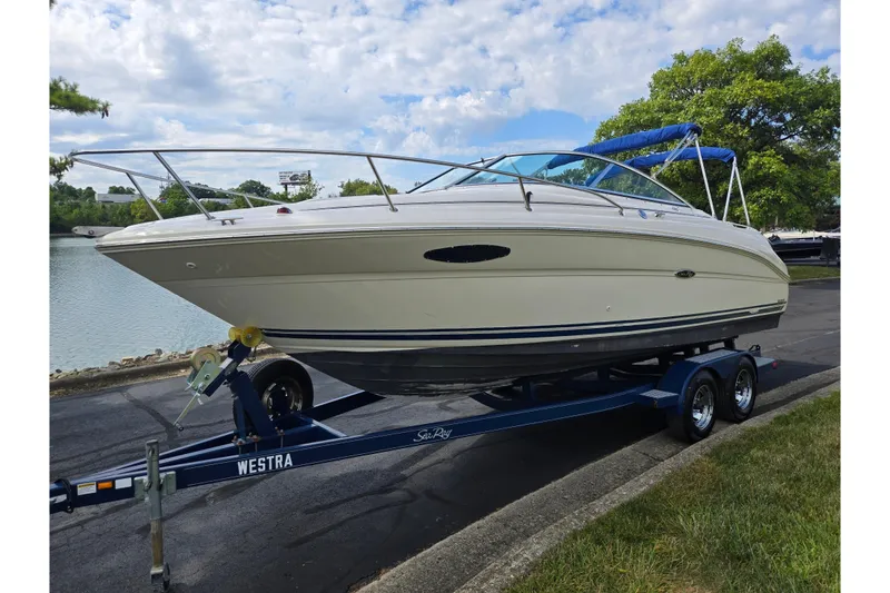 Slide: The Image of 2002 Sea Ray 225 Weekender boat on trailer, parked near a lake. - 8