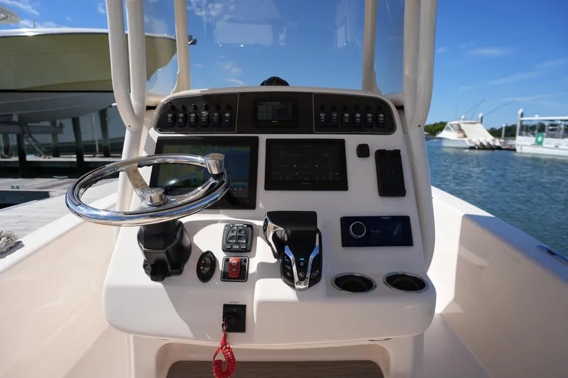 Slide: The Image of 2024 Grady-White 251 Coastal Explorer boat dashboard with steering wheel and controls. - 26