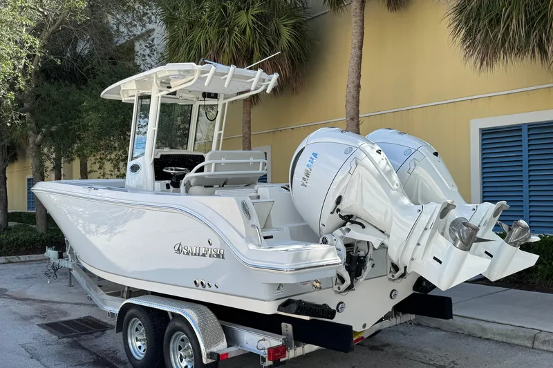 Slide: The Image of 2026 Sailfish 252 boat with dual Yamaha engines on a trailer, parked near palm trees. - 1