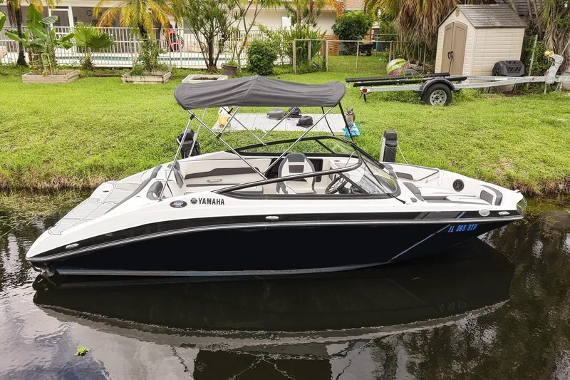 Slide: The Image of 2023 Yamaha Boats SX195 in a serene canal setting, featuring sleek design and modern amenities. - 25
