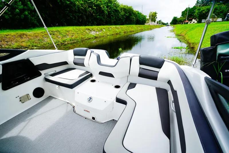 Slide: The Image of 2023 Yamaha Boats SX195 interior with sleek seating by a scenic waterway. - 7