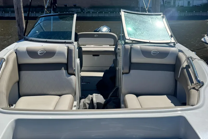 Slide: The Image of 2022 Crownline Eclipse E235 XS boat interior with beige seating and open windshield. - 10