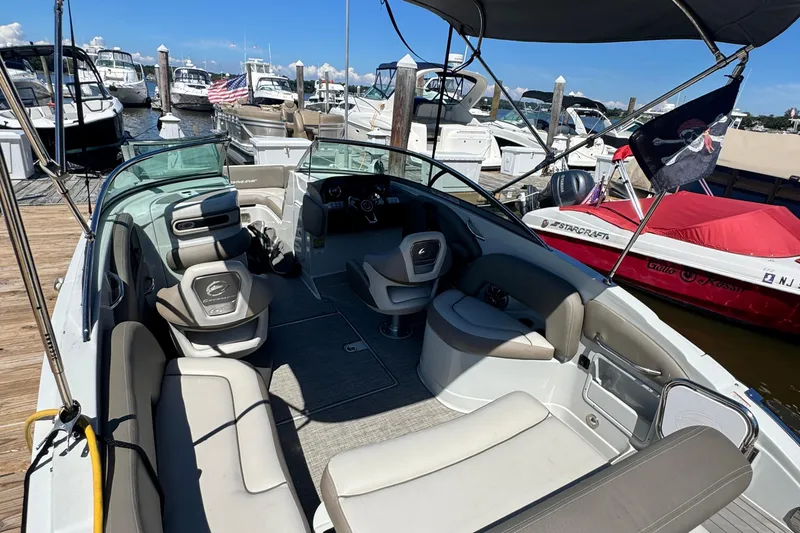 Slide: The Image of 2022 Crownline Eclipse E235 XS boat interior at marina, featuring spacious seating and helm. - 13