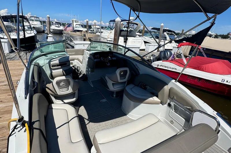 Slide: The Image of 2022 Crownline Eclipse E235 XS boat interior at marina, featuring seating and helm. - 9