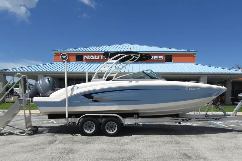 The Image of 2022 Chaparral 23 SSi boat on trailer, parked outside a dealership under a clear blue sky. - 0
