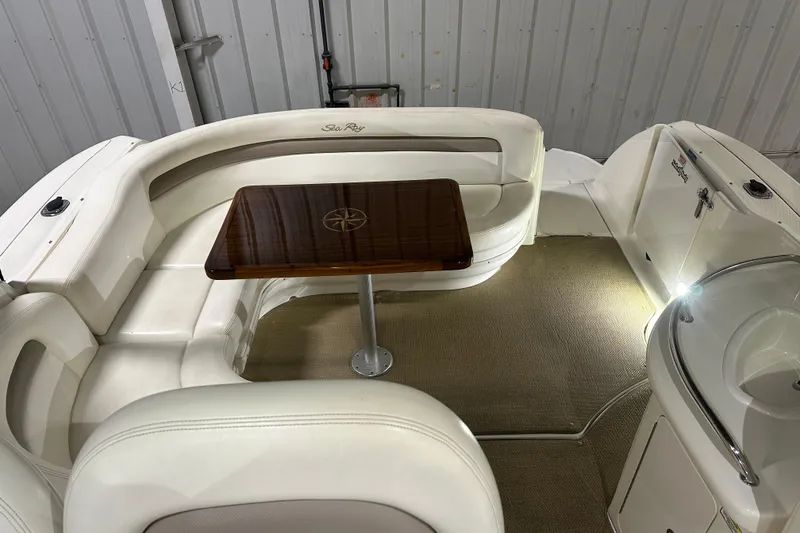 Slide: The Image of 2004 Sea Ray 340 Sundancer interior with white seating and wooden table in a cozy cabin. - 13