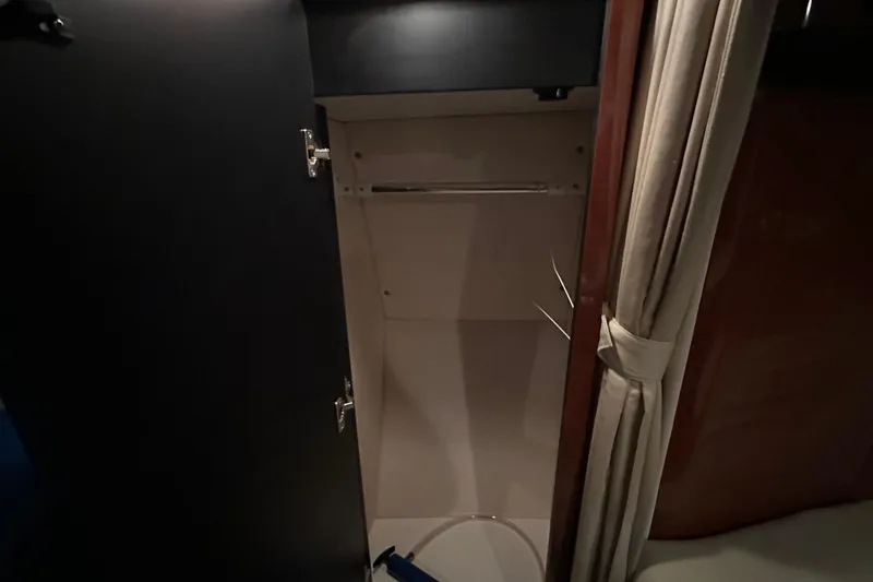 Slide: The Image of Open closet inside 2004 Sea Ray 340 Sundancer boat cabin, featuring dark wood and curtain. - 44
