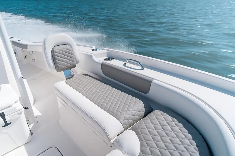 Slide: The Image of 2026 Caymas 24 HB boat interior with quilted seating, cruising on water. - 9