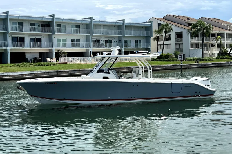 Slide: The Image of 2020 Pursuit S 328 Sport boat cruising near waterfront buildings. - 1