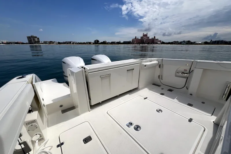 Slide: The Image of 2020 Pursuit S 328 Sport boat deck with dual engines, calm waters, and distant shoreline. - 11