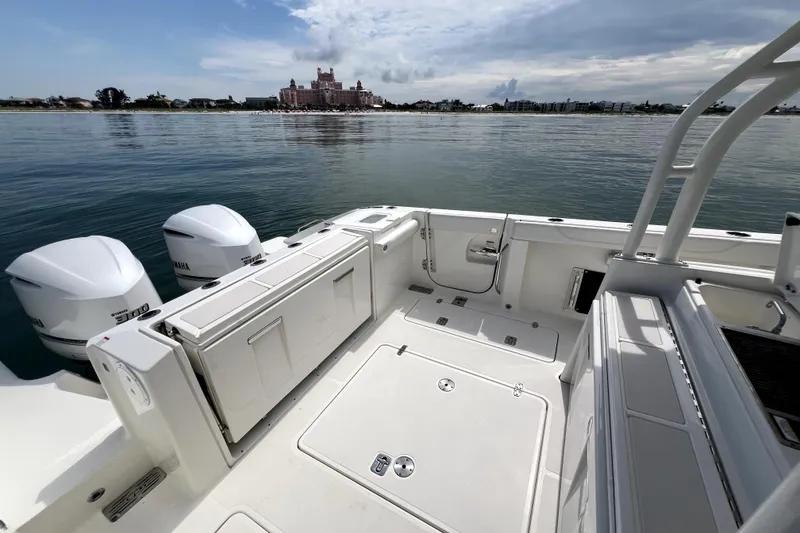 Slide: The Image of 2020 Pursuit S 328 Sport boat with dual Yamaha engines, docked near a scenic waterfront. - 12