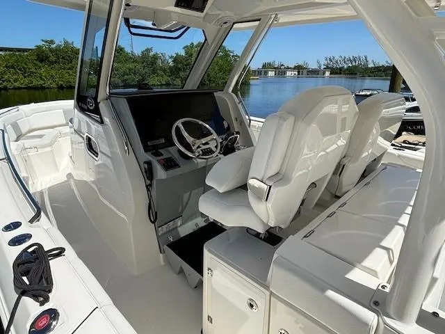 Slide: The Image of 2020 Pursuit S 328 Sport boat interior with helm, white seating, and water view. - 15