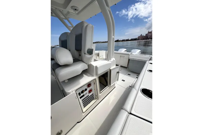 Slide: The Image of 2020 Pursuit S 328 Sport boat interior with seating and control panel, docked by calm waters. - 19