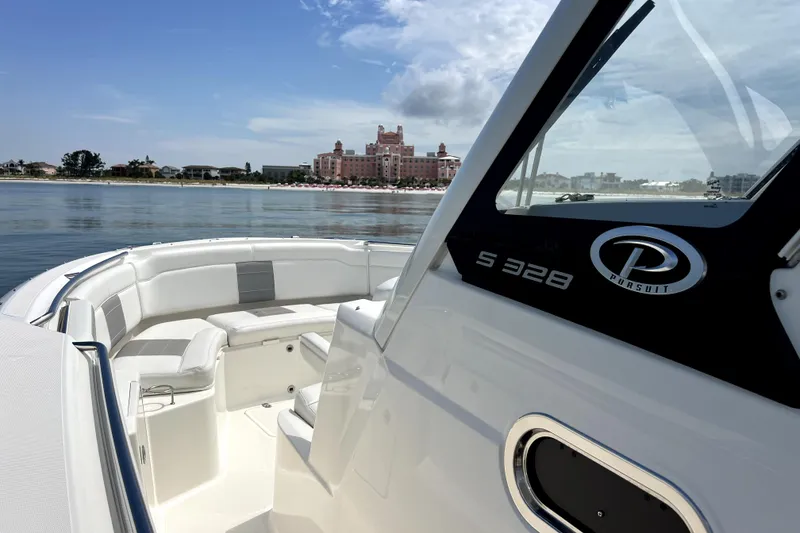 Slide: The Image of 2020 Pursuit S 328 Sport boat on calm water near a coastal building. - 22