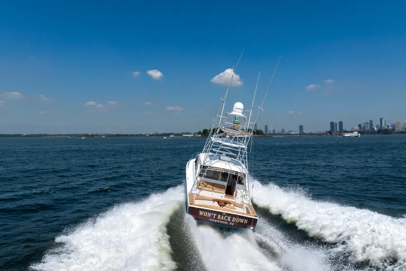 Slide: The Image of 2012 Cabo 44 Hardtop Express cruising on open water with city skyline in background. - 10