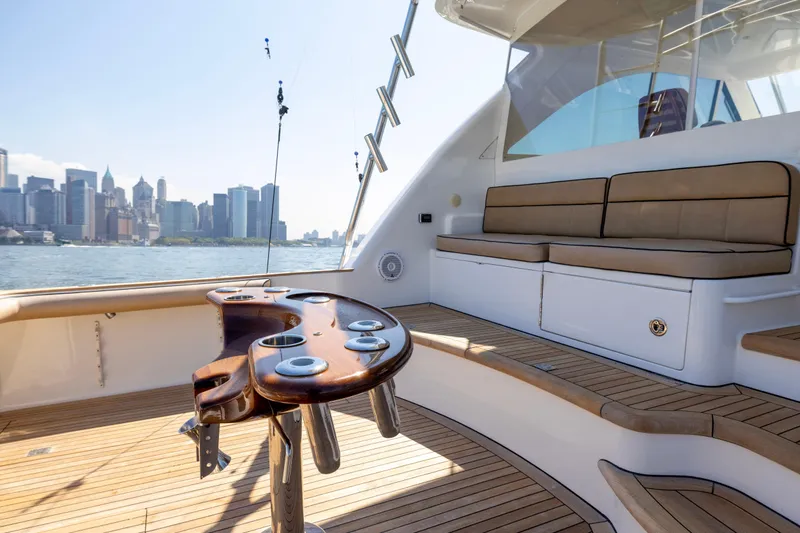 Slide: The Image of 2012 Cabo 44 Hardtop Express yacht with wooden deck and rod holders, city skyline in background. - 104