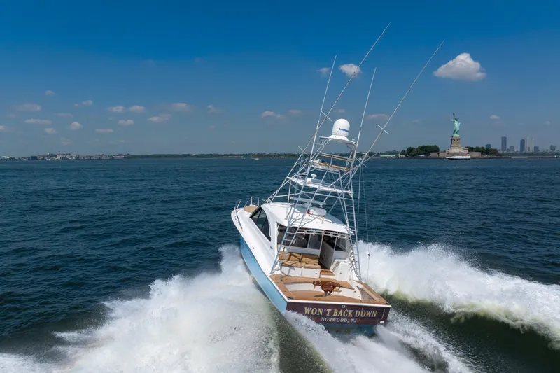 Slide: The Image of 2012 Cabo 44 Hardtop Express yacht cruising near the Statue of Liberty on a sunny day. - 12