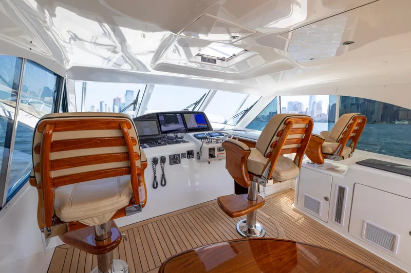 Slide: The Image of Luxurious 2012 Cabo 44 Hardtop Express yacht interior with helm, wooden seats, and city skyline view. - 125