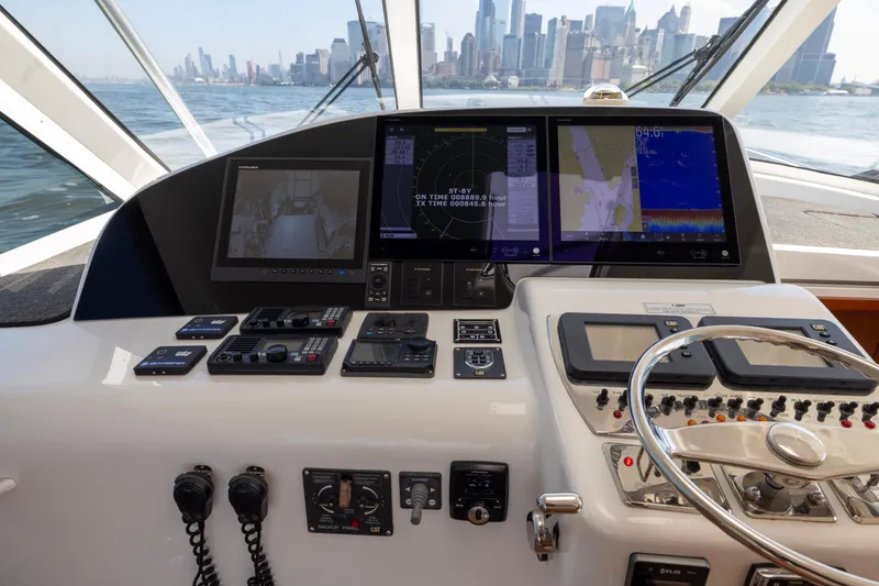 Slide: The Image of Helm of 2012 Cabo 44 Hardtop Express with navigation screens and controls, city skyline view. - 135