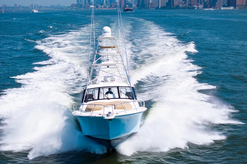 Slide: The Image of 2012 Cabo 44 Hardtop Express cruising on open water with city skyline backdrop. - 14
