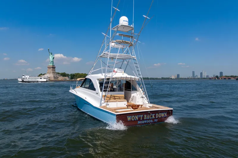 Slide: The Image of 2012 Cabo 44 Hardtop Express yacht near Statue of Liberty, sunny day, New York City skyline. - 148