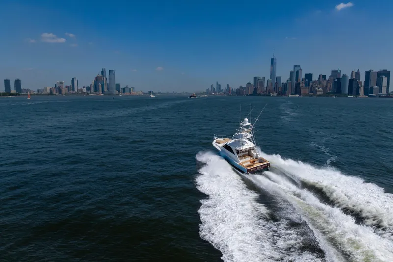 Slide: The Image of 2012 Cabo 44 Hardtop Express yacht cruising near city skyline on a sunny day. - 21