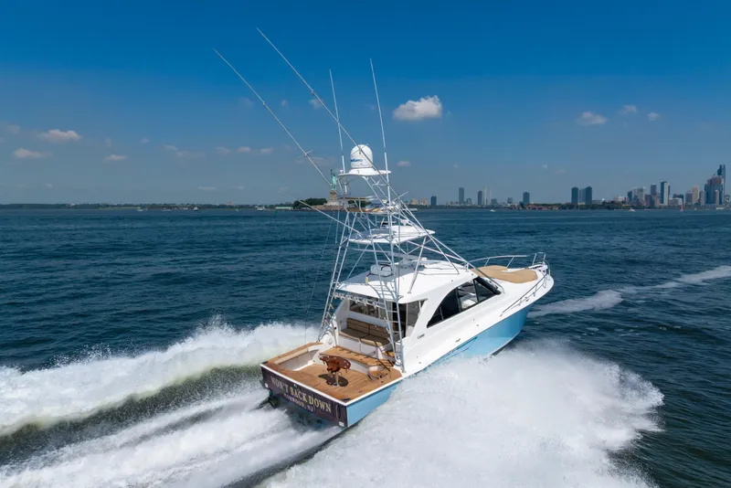 Slide: The Image of 2012 Cabo 44 Hardtop Express yacht cruising near city skyline on a sunny day. - 25