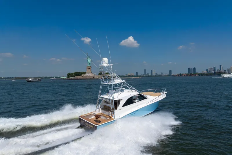 Slide: The Image of 2012 Cabo 44 Hardtop Express yacht cruising near Statue of Liberty, clear blue sky. - 4