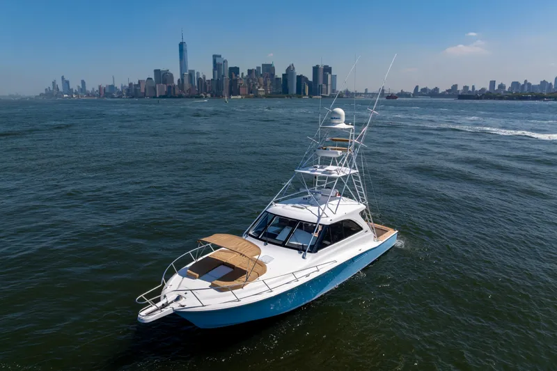 Slide: The Image of 2012 Cabo 44 Hardtop Express yacht cruising near city skyline on a sunny day. - 41