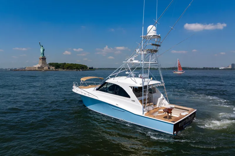 Slide: The Image of 2012 Cabo 44 Hardtop Express yacht near Statue of Liberty on sunny day. - 44