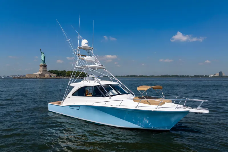 Slide: The Image of 2012 Cabo 44 Hardtop Express yacht near Statue of Liberty on sunny day. - 48