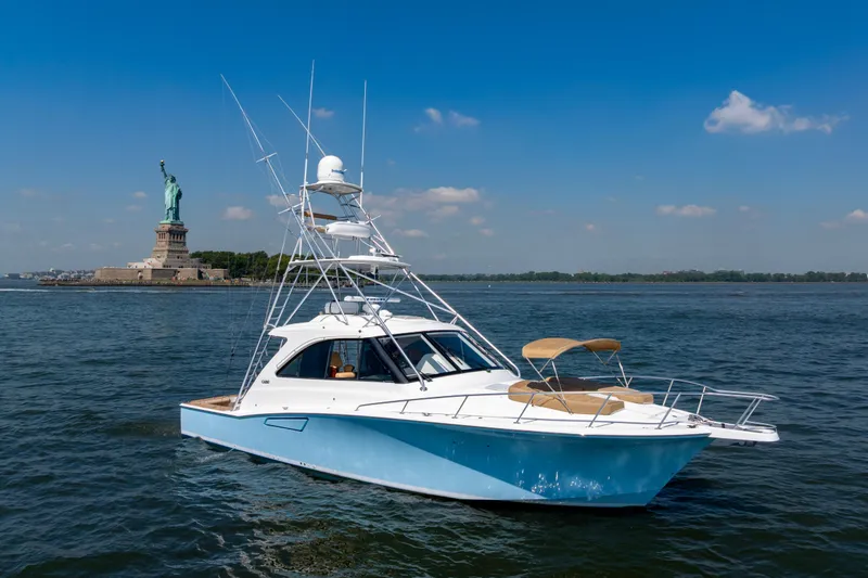 Slide: The Image of 2012 Cabo 44 Hardtop Express yacht near Statue of Liberty on a sunny day. - 49