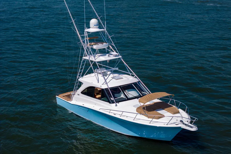 Slide: The Image of 2012 Cabo 44 Hardtop Express yacht on open water, featuring a sleek design and tower. - 51