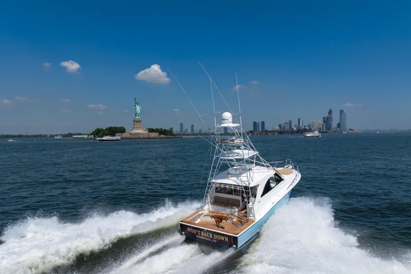 Slide: The Image of 2012 Cabo 44 Hardtop Express yacht near Statue of Liberty, New York City skyline in background. - 6