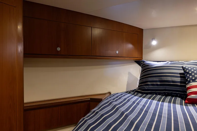 Slide: The Image of Cozy cabin interior of 2012 Cabo 44 Hardtop Express with striped bedding and American flag pillow. - 73