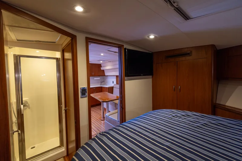 Slide: The Image of Luxurious cabin interior of 2012 Cabo 44 Hardtop Express with striped bedding and wooden cabinets. - 74