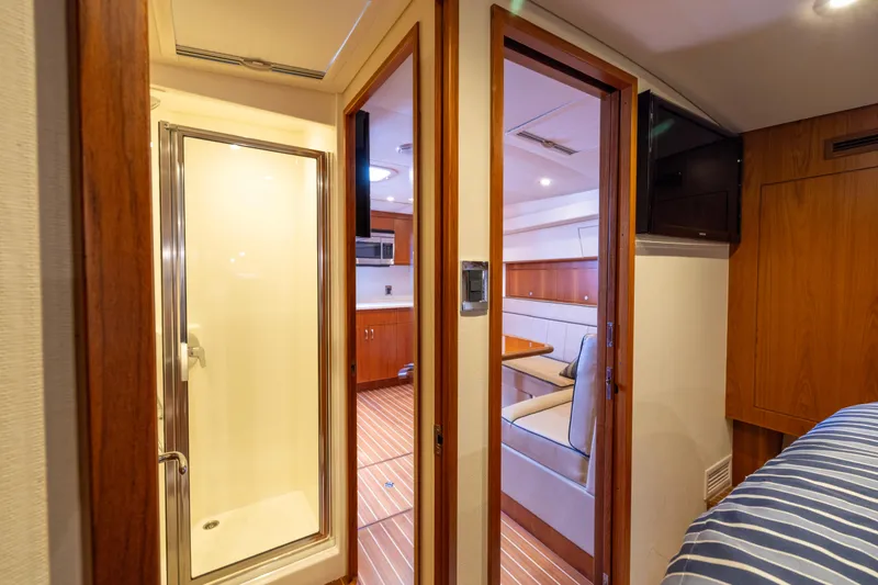 Slide: The Image of Interior of 2012 Cabo 44 Hardtop Express yacht with wood cabinetry and striped bedding. - 76