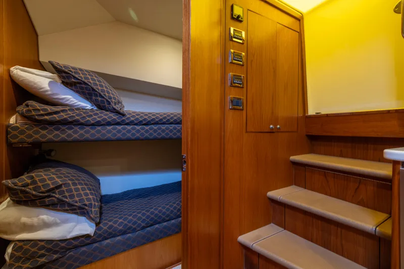 Slide: The Image of Interior of 2012 Cabo 44 Hardtop Express with cozy bunk beds and wooden finish. - 85